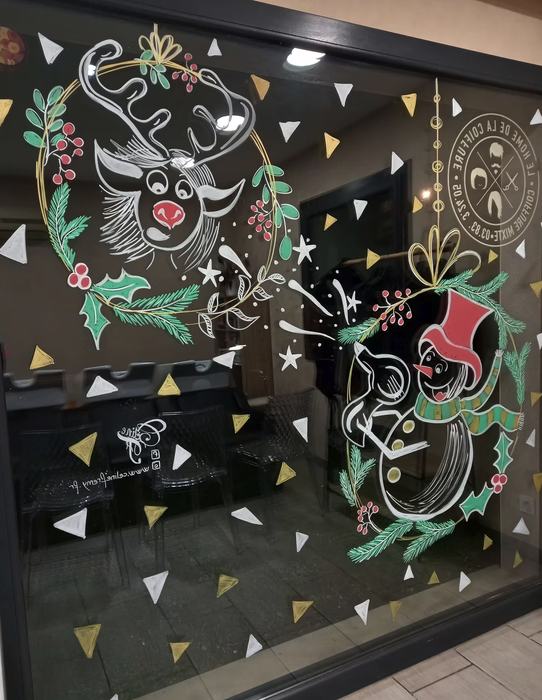 Vitrine peinte avec renne et bonhomme de neige dans une couronne